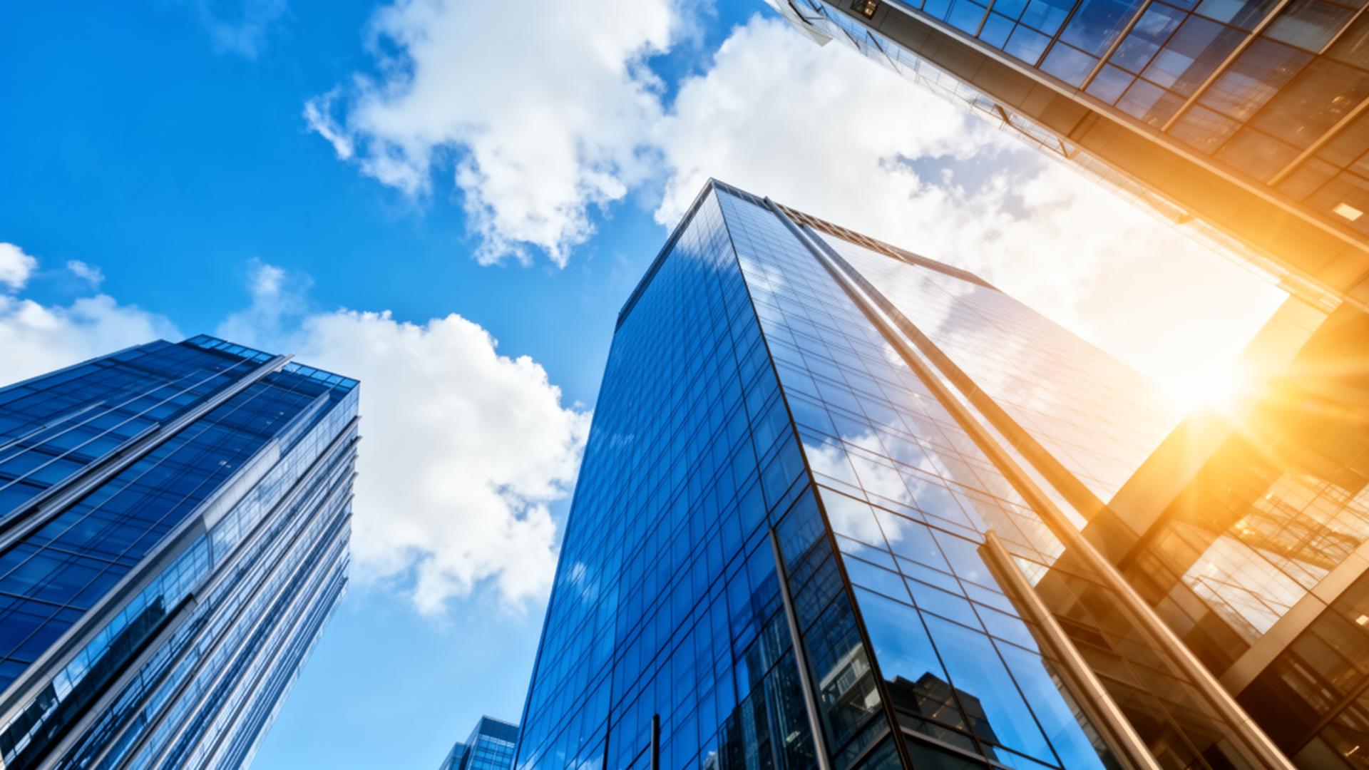 Glass skyscrapers rising into a bright blue corporate sky
